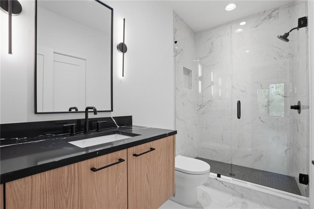 3293 Lenox Place Northeast Atlanta, GA 30324 - Photo 26 of 40 a bathroom with a granite countertop sink a toilet a mirror and shower
