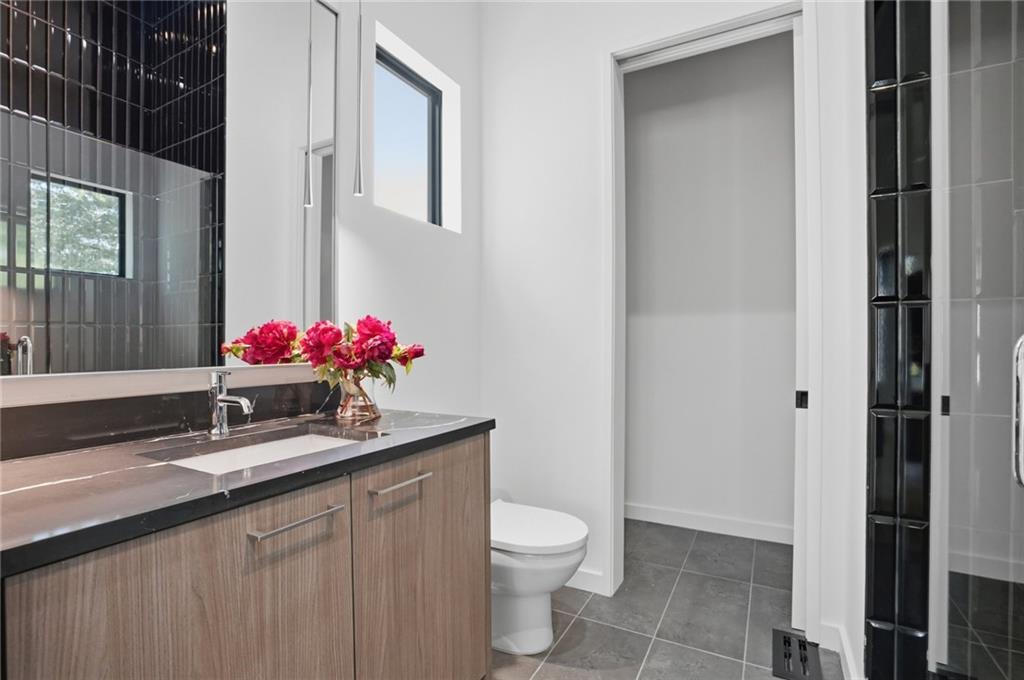 3293 Lenox Place Northeast Atlanta, GA 30324 - Photo 34 of 40 a bathroom with a granite countertop sink a toilet and a shower