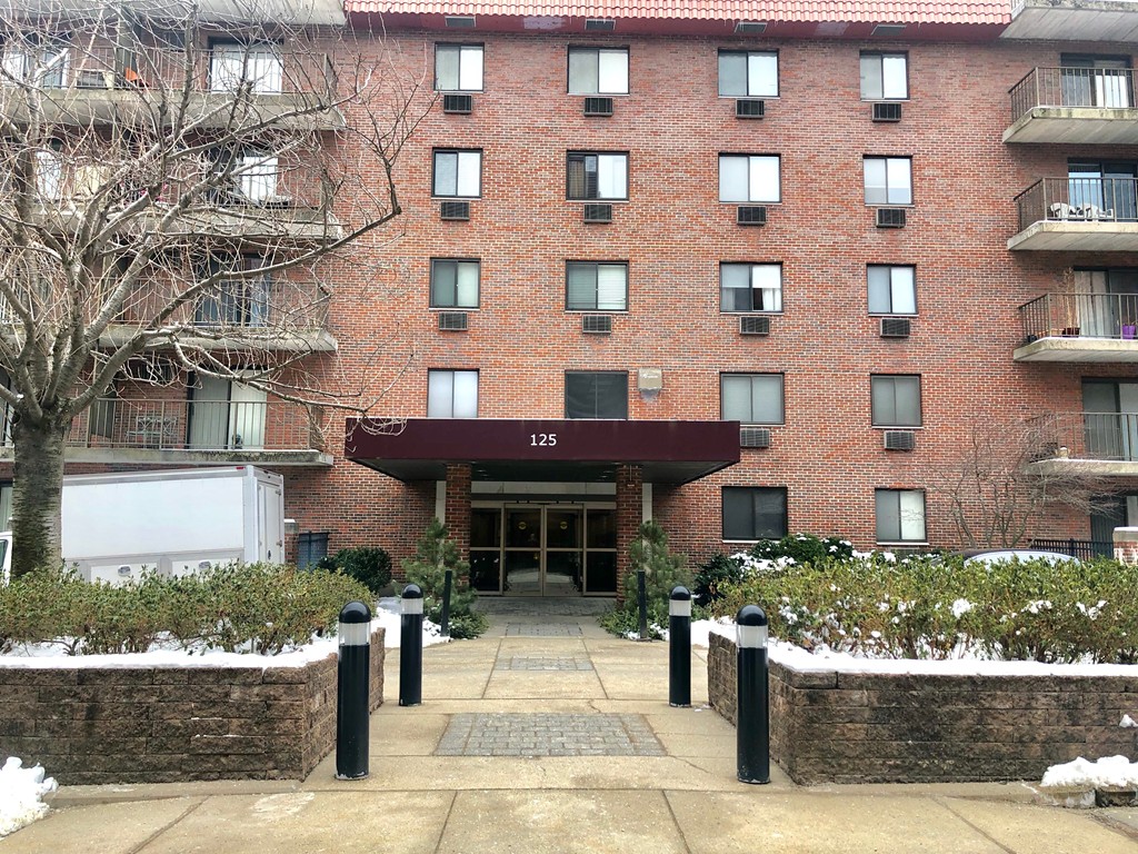 125 Pleasant Street, Unit 309 Brookline, MA 02446 - Photo 1 of 9 a front view of a building with a garden