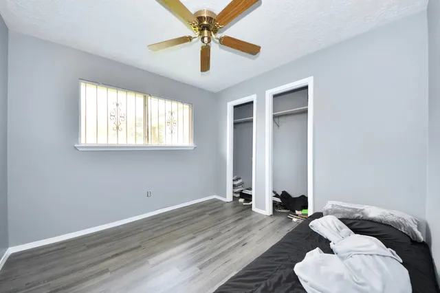 an empty room with wooden floor fan and windows
