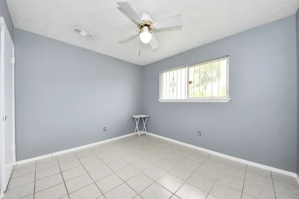an empty room with windows and ceiling fan