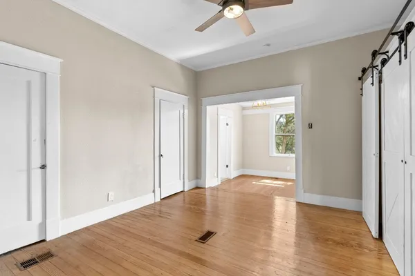 an empty room with wooden floor closet and windows