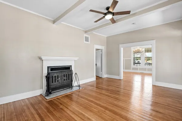 a view of an empty room with a window and wooden floor