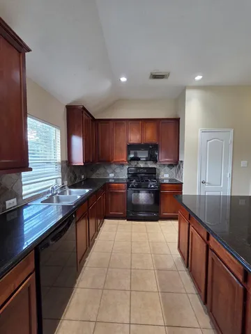 a large kitchen with stainless steel appliances granite countertop a sink stove and cabinets