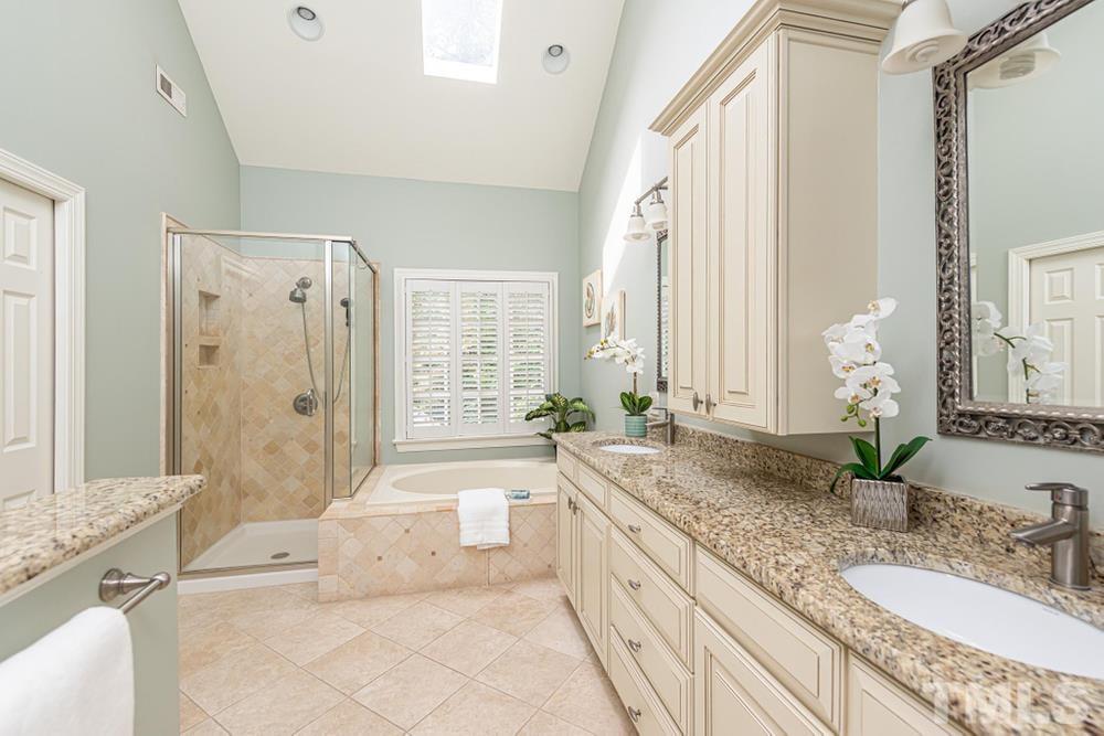 313 Jellison Court Raleigh, NC 27615 - Photo 20 of 30 Primary Bathroom with dual vanity sinks, garden tub, walk in shower, and skylights.