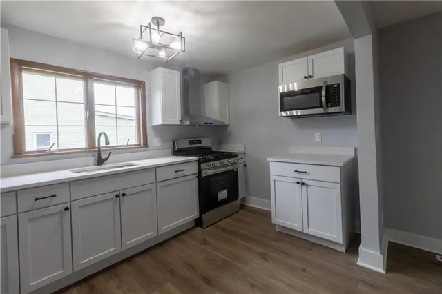 a kitchen with stainless steel appliances white cabinets a sink and a stove