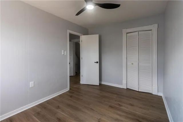 an empty room with wooden floor cabinet and windows