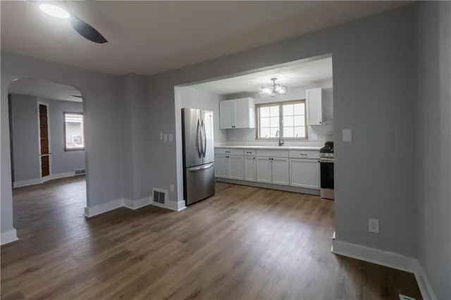 an empty room with wooden floor and a kitchen
