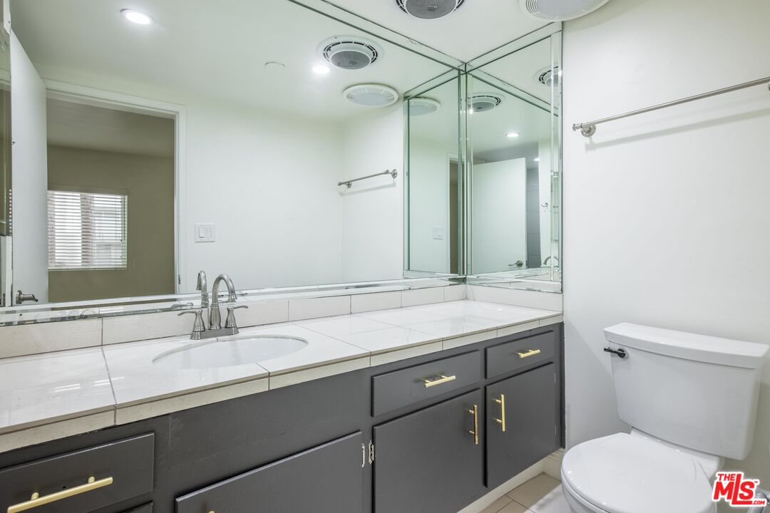 148 South Reeves Drive, Unit 4 Beverly Hills, CA 90212 - Photo 13 of 15 a bathroom with a granite countertop sink a toilet and a mirror