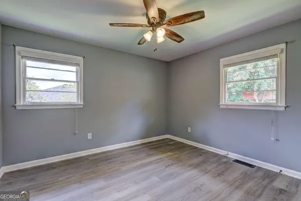 an empty room with wooden floor closet and windows