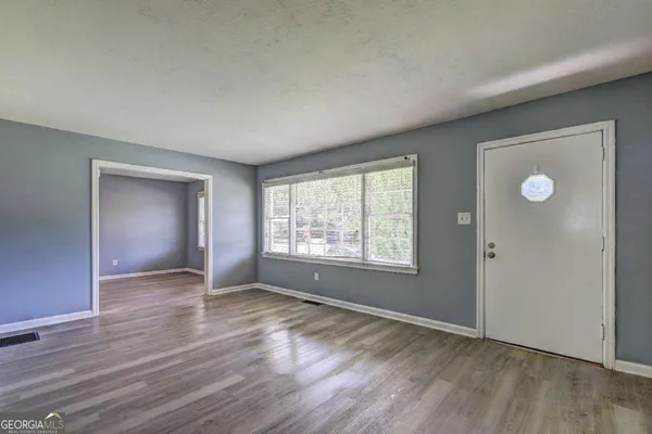 an empty room with wooden floor and windows