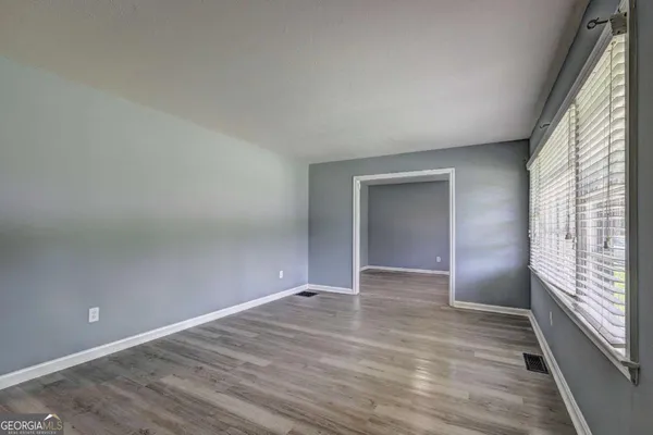 a view of an empty room with wooden floor and a window