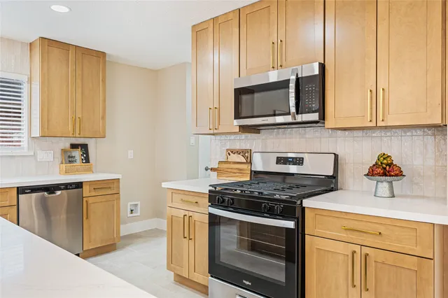 a kitchen with stainless steel appliances granite countertop white cabinets a stove top oven a sink and dishwasher