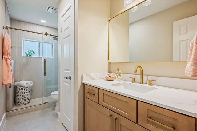 a bathroom with a granite countertop sink a toilet a shower and a mirror