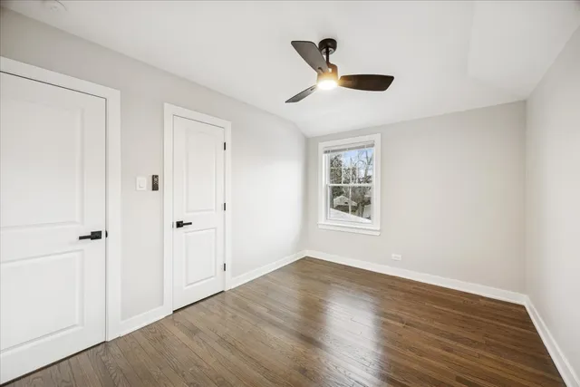 an empty room with wooden floor cabinet and windows
