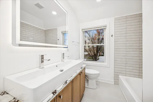 a bathroom with a sink a toilet a mirror and a tub