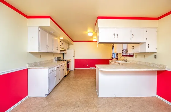 a kitchen with granite countertop a stove a sink and white cabinets
