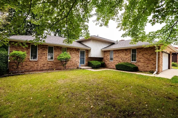 a front view of a house with yard tree and outdoor seating