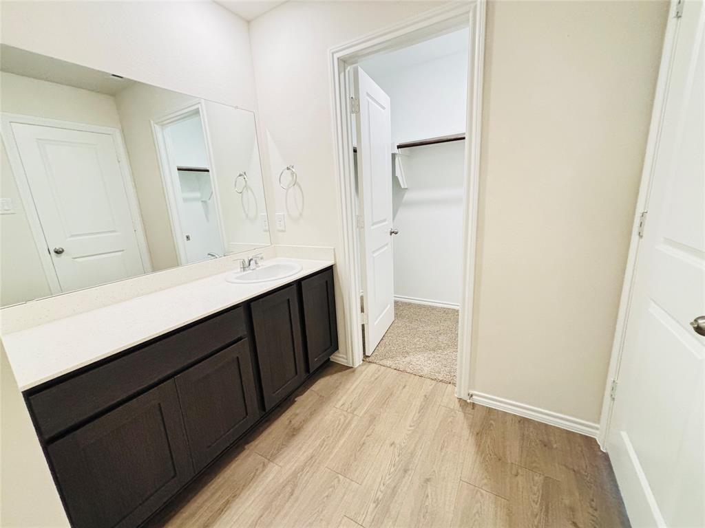 120 Redwood Road Princeton, TX 75407 - Photo 15 of 24 Bathroom vanity featuring a single sink, light countertop, dark cabinetry, and an expansive wall mirror