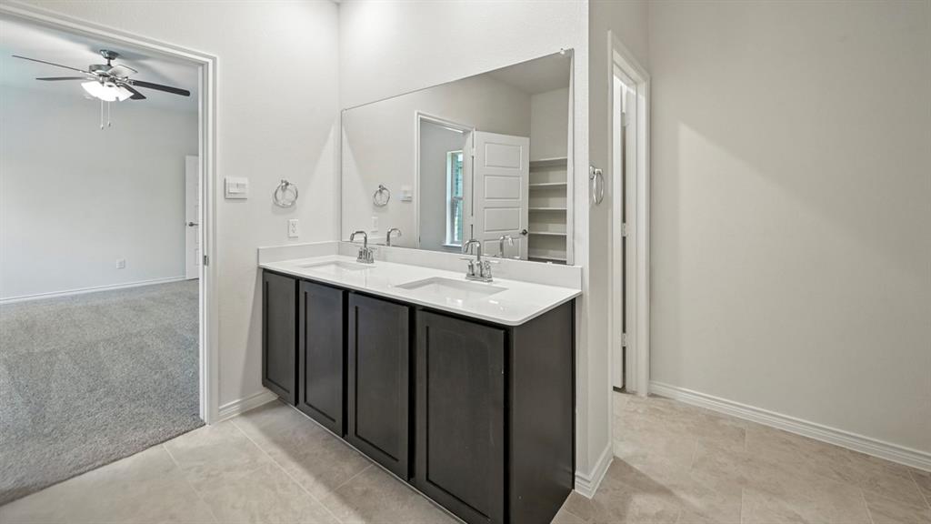 412 Carthage Street Caddo Mills, TX 75135 - Photo 26 of 32 Double vanity with integrated sinks, white countertops, dark wood-finish cabinetry, and a large wall-mounted mirror
