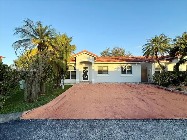 a front view of a house with a yard and palm tree