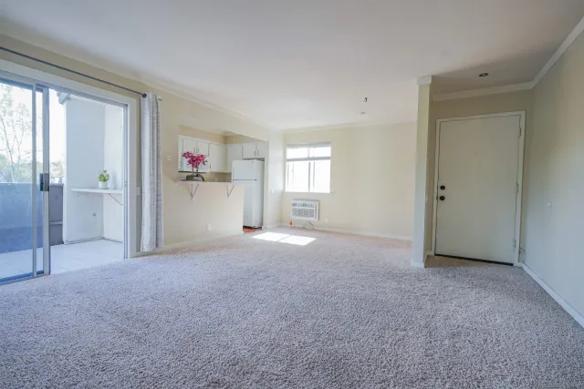 a view of empty room with windows and refrigerator