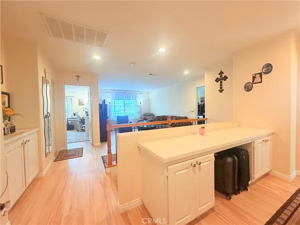 a large kitchen with kitchen island a sink dishwasher a stove a refrigerator and white cabinets with wooden floor