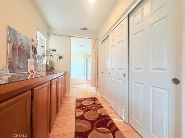 a view of a hallway with wooden floor and a bathroom