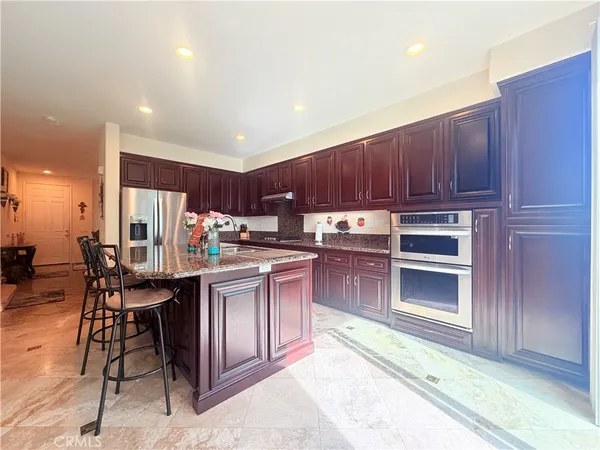 a kitchen with kitchen island granite countertop wooden cabinets stainless steel appliances and a counter top space