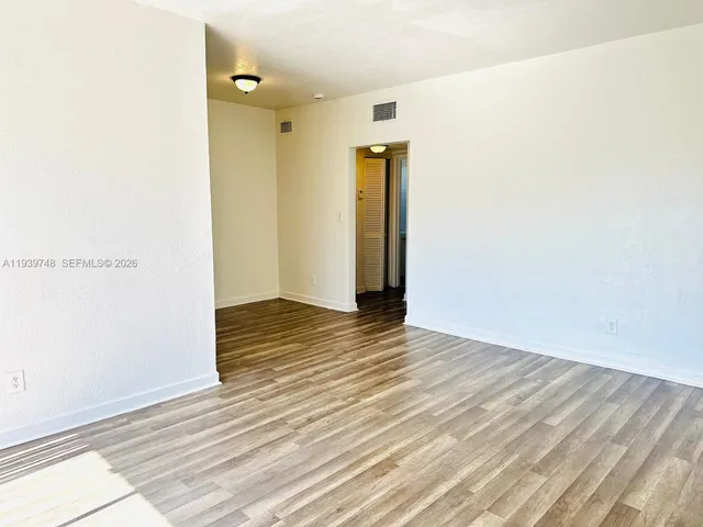 a view of an empty room with wooden floor
