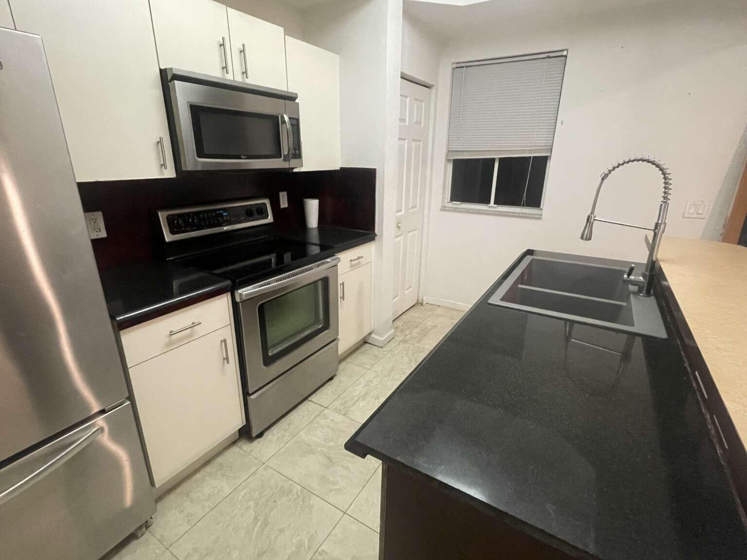 2944 Hidden Hills Road, Unit 1604 West Palm Beach, FL 33411 - Photo 3 of 11 a kitchen with a sink stove and microwave