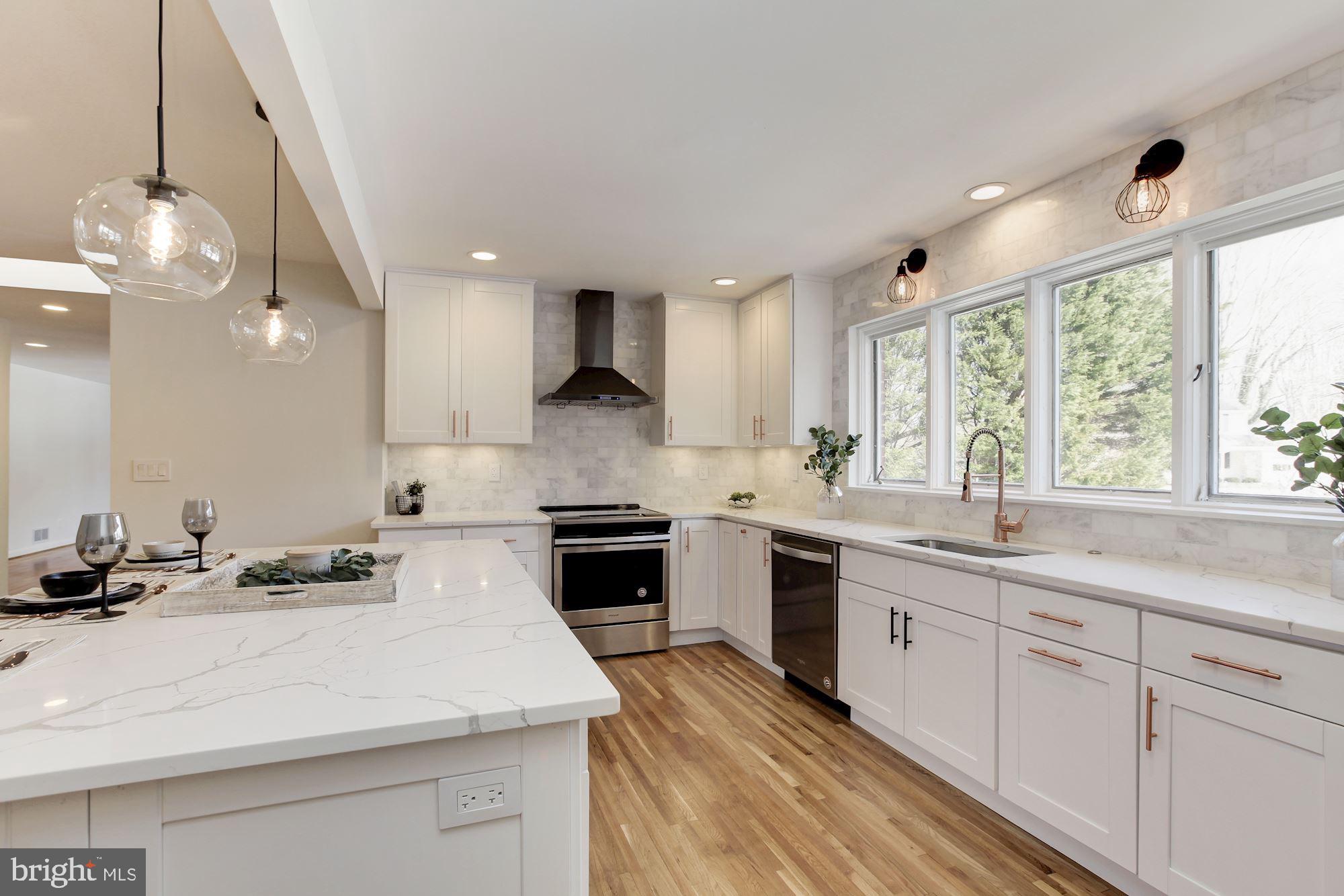 a kitchen with a sink stainless steel appliances cabinets and a large window