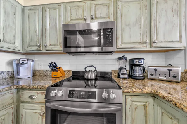 a kitchen with granite countertop white cabinets and stainless steel appliances