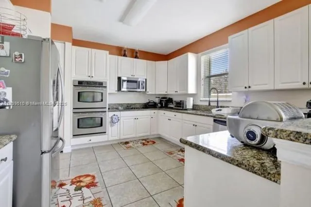 a kitchen with stainless steel appliances granite countertop a sink stove refrigerator and cabinets