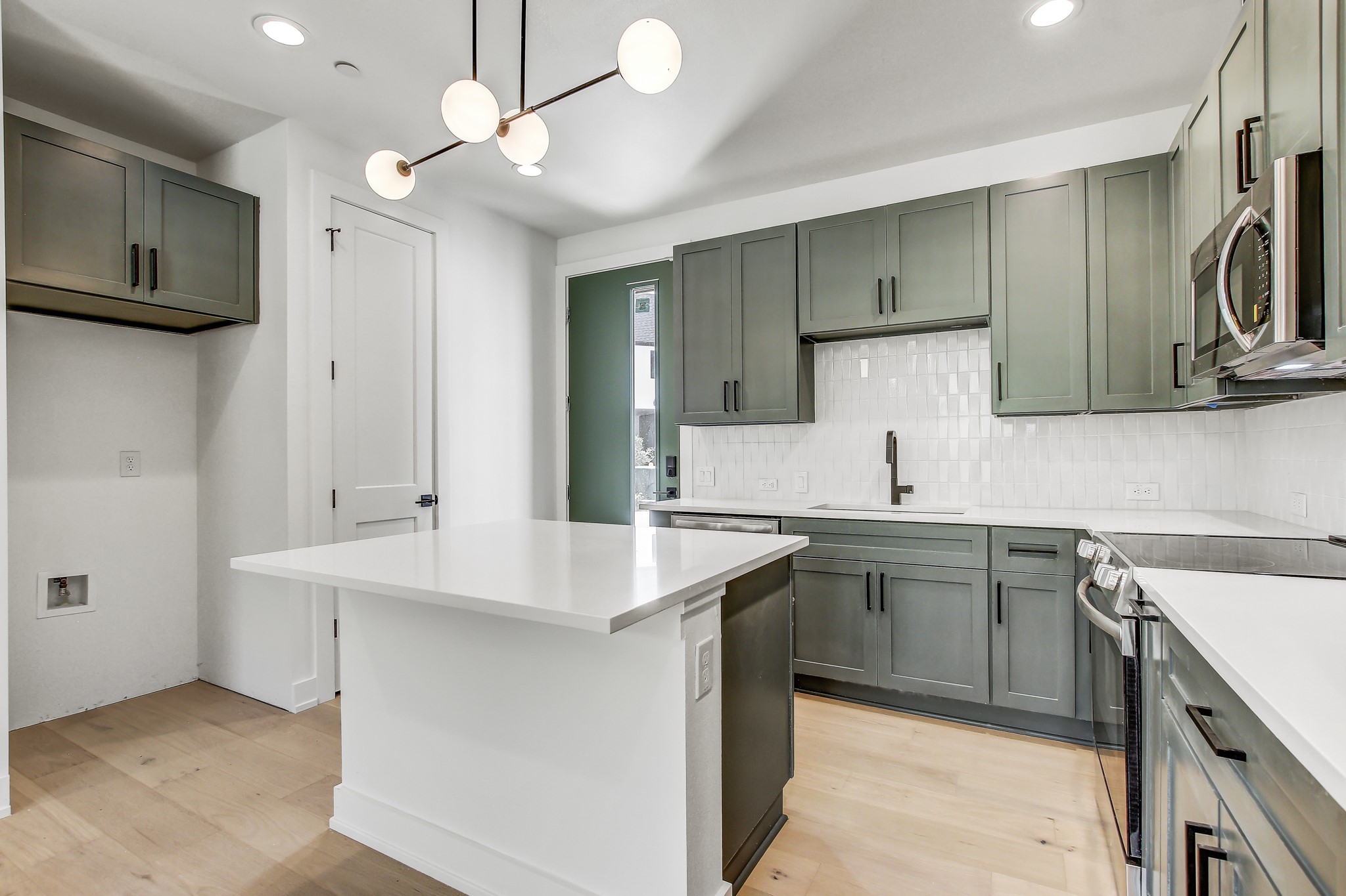 4127 East 12th Street, Unit 3 Austin, TX 78721 - Photo 3 of 29 Kitchen featuring appliances with stainless steel finishes, a sink, light wood-style floors, light countertops, and decorative backsplash