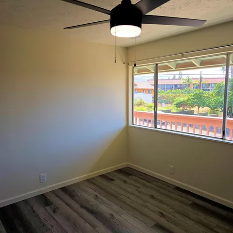 a view of empty room with wooden floor and fan