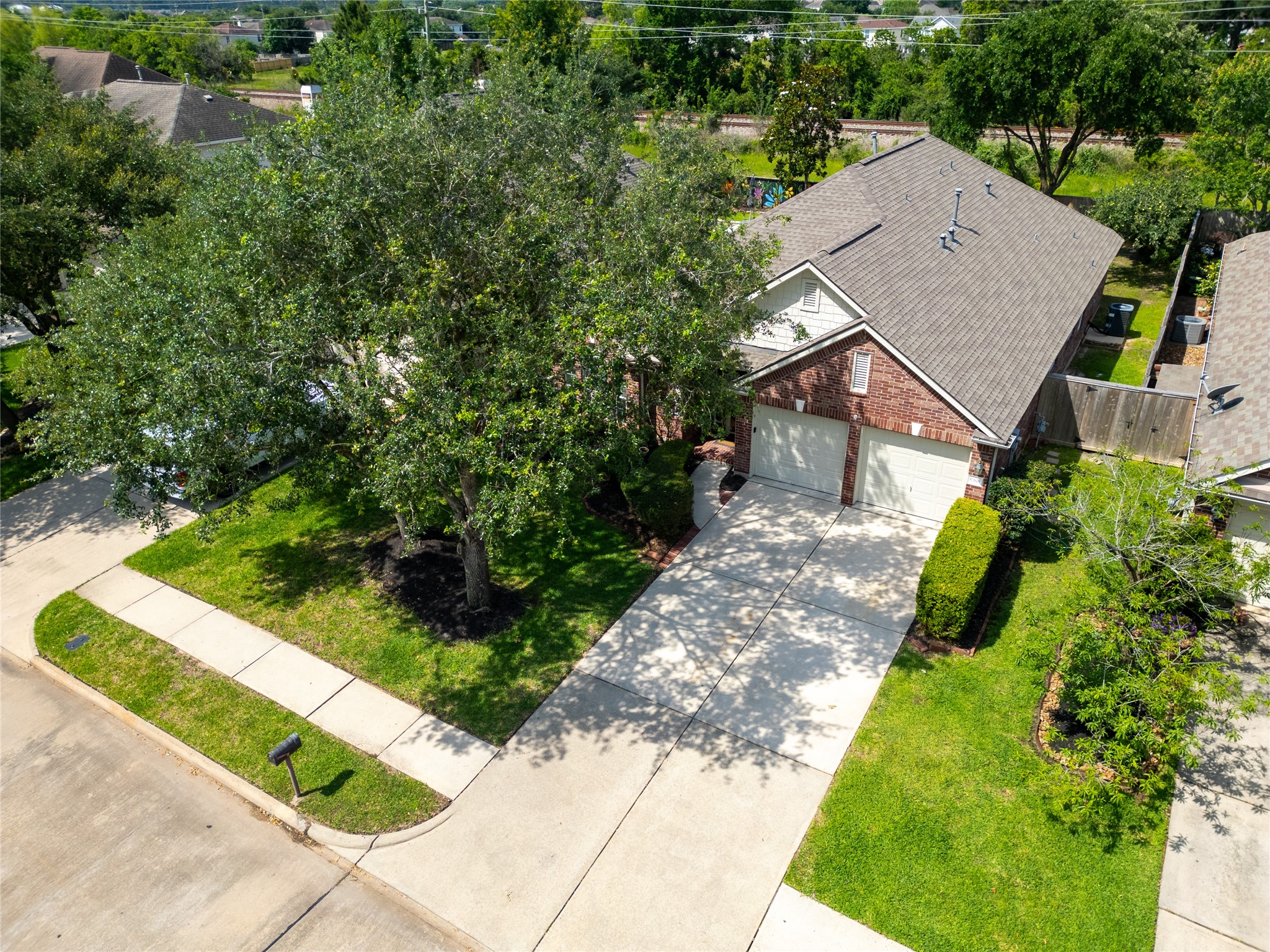 10619 Crownsedge Drive Spring, TX 77379 - Photo 35 of 38 This photo features a charming brick home with a spacious driveway and two-car garage. The front yard is well-maintained with lush greenery and mature trees, offering ample shade. The house is situated in a quiet, suburban neighborhood.