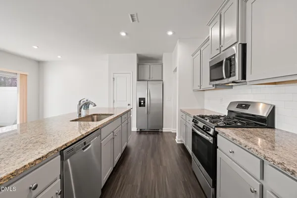 a kitchen with stainless steel appliances granite countertop a stove a sink and a refrigerator