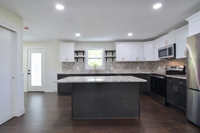 a kitchen with stainless steel appliances granite countertop a sink a stove and a microwave