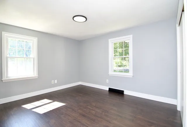 a view of an empty room with wooden floor and a fireplace