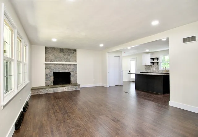 a large kitchen with a center island wooden floor stainless steel appliances and a window