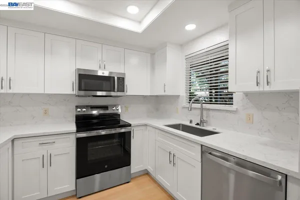 a kitchen with sink a microwave a stove and cabinets