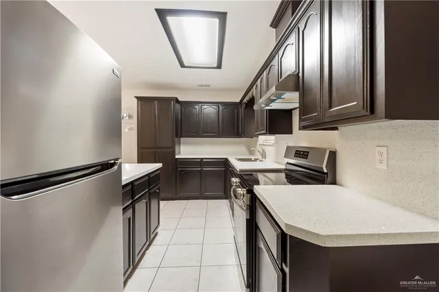 a kitchen with stainless steel appliances a refrigerator a stove a sink dishwasher and white countertops with wooden floor