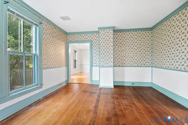 a view of empty room with wooden floor and fan