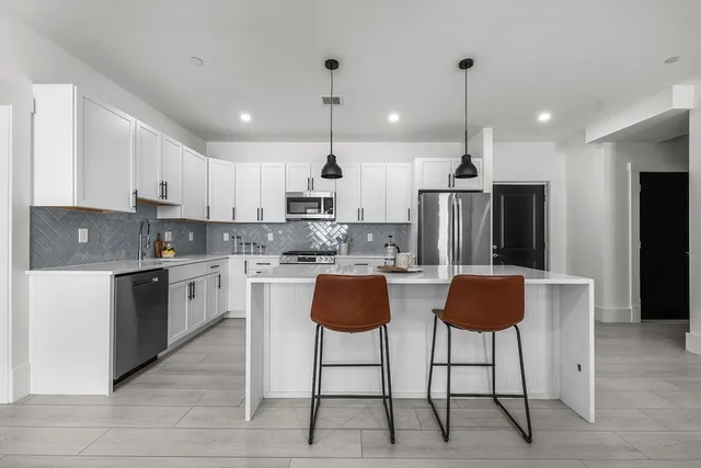 a kitchen with kitchen island granite countertop a counter space a refrigerator a stove a oven a sink cabinets and a counter top space