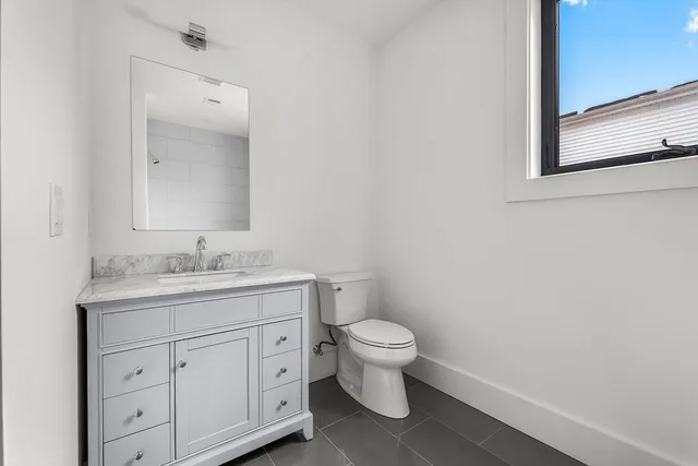 a bathroom with a granite countertop toilet a sink and a mirror