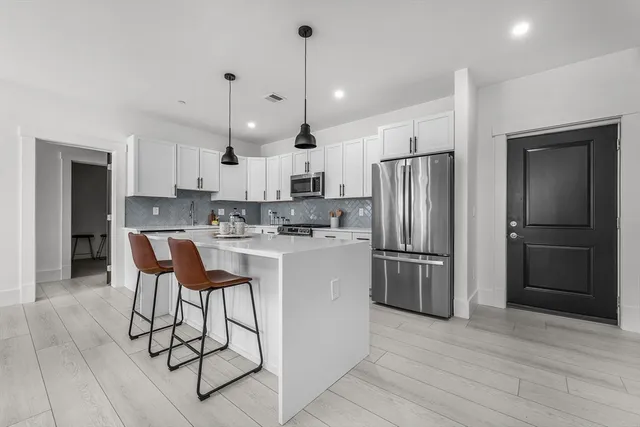 a kitchen with stainless steel appliances granite countertop a refrigerator a stove a sink and a refrigerator with wooden floor