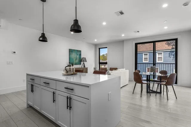 a kitchen with a dining table chairs wooden floor and appliances