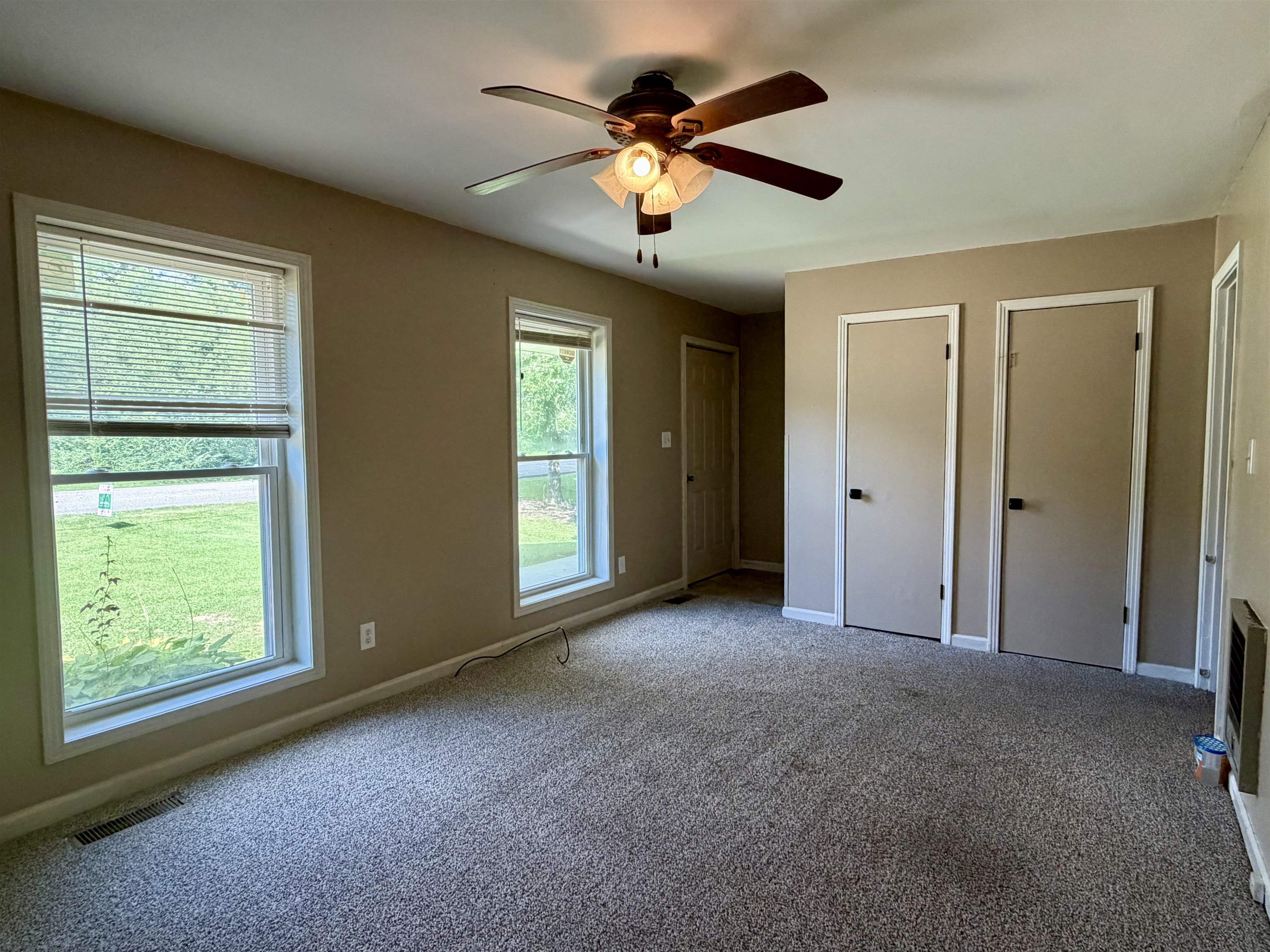 355 Purdy Road Selmer, TN 38375 - Photo 2 of 14 Bright room featuring neutral carpet flooring, two windows with blinds, a ceiling fan with integrated lighting, and two closet doors