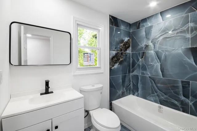a bathroom with a toilet sink vanity tub and mirror